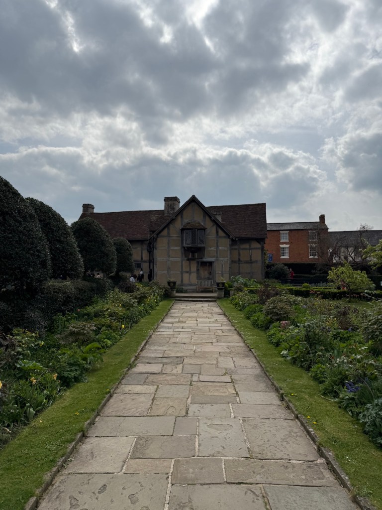 The garden path leads to Shakespeare's birthplace at the centre showing a mostly sunny, cloudy day