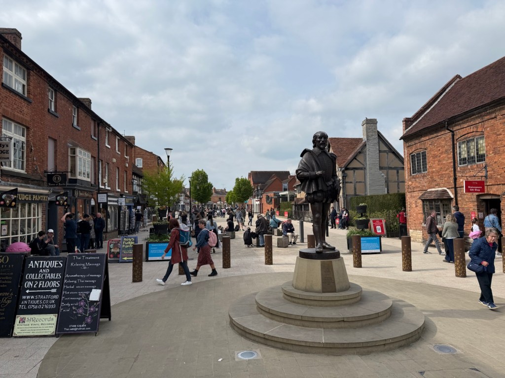 Statue of William Shakespeare with busy street behind.