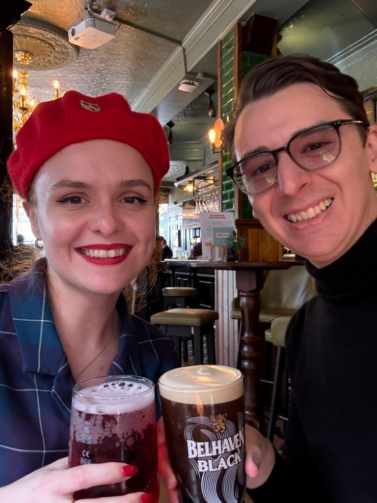 Two people pose with drinks in hand