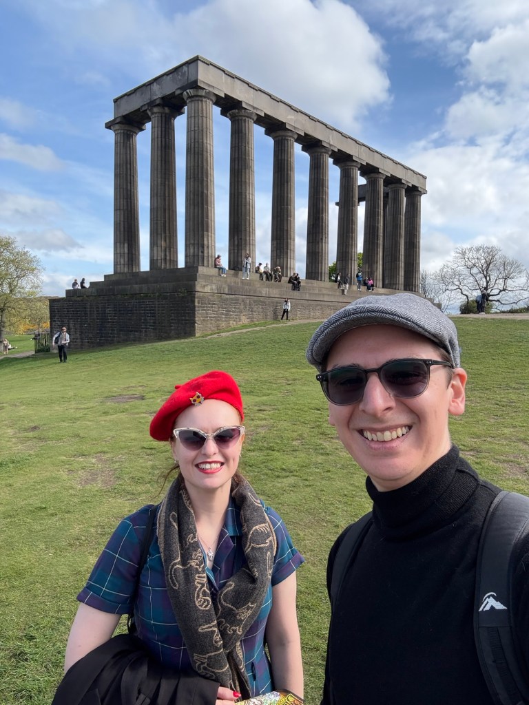 Two people pose in front of the National monument of Scotland