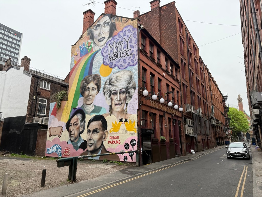 A side-view of the Molly House with a mural of several notable Queer icons: Anna Phylactic (top), Foo Foo Lamar (top right), Emmaline Pankhurst (top left), Quentin Crisp (bottom left) and Alan Turing (bottom).