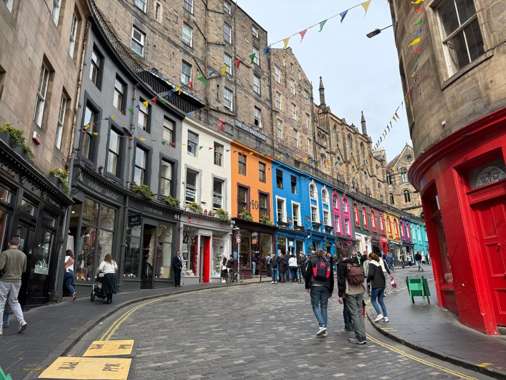 Different coloured 18th century shop fronts along a curved cobblestone street