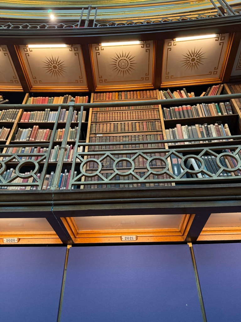 A balcony showing a wall lined with books and a book door